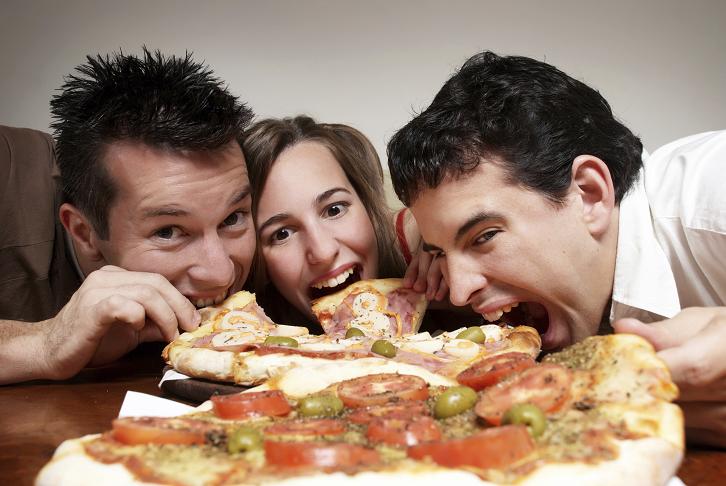The cheerful company of youth eating a pizza